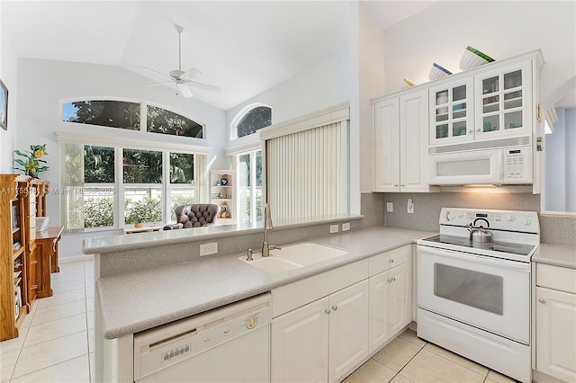 kitchen with tasteful backsplash, light tile patterned floors, a peninsula, white appliances, and a sink