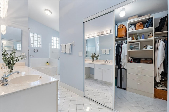 full bath with vaulted ceiling, a spacious closet, two vanities, and a sink