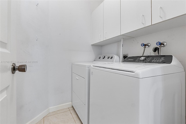 clothes washing area featuring washer and dryer, baseboards, cabinet space, and light tile patterned floors