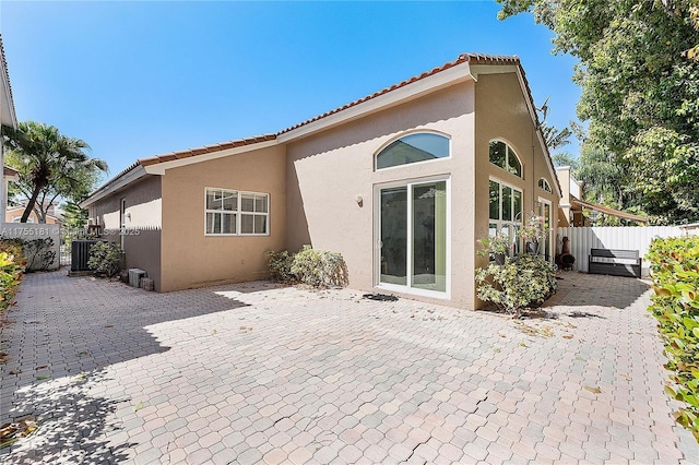 back of house featuring a tiled roof, a patio area, fence, and stucco siding