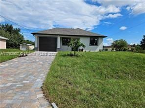 view of front of house featuring driveway, an attached garage, and a front yard