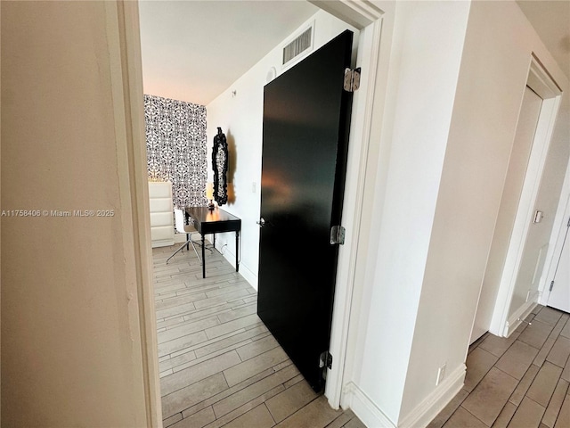 corridor with wood finish floors, visible vents, and baseboards