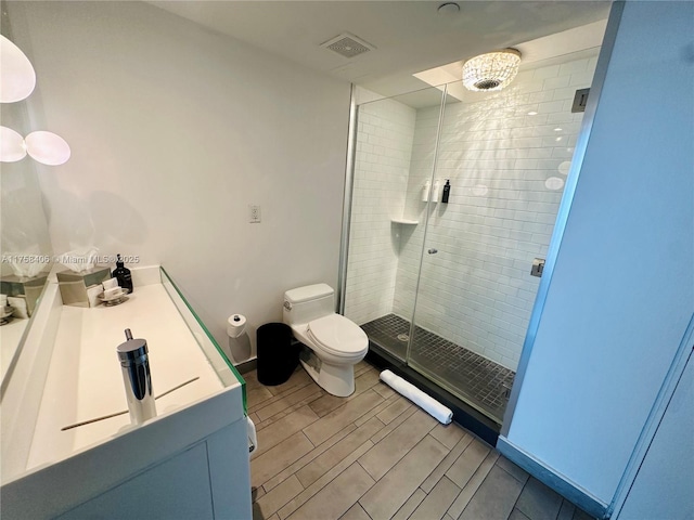 full bath with vanity, visible vents, wood tiled floor, a shower stall, and toilet