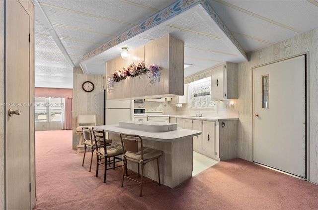 kitchen with white appliances, a sink, light countertops, light colored carpet, and a center island