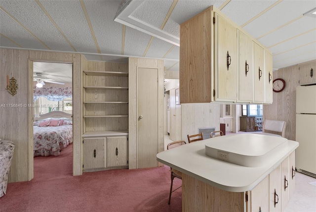 kitchen with a breakfast bar, wood walls, freestanding refrigerator, and a textured ceiling