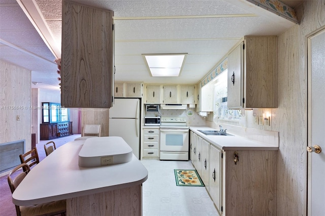 kitchen featuring visible vents, under cabinet range hood, a sink, white appliances, and light countertops