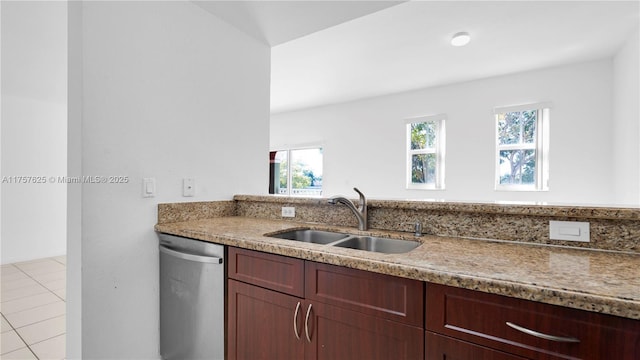 kitchen with tile patterned floors, dishwasher, light stone countertops, and a sink