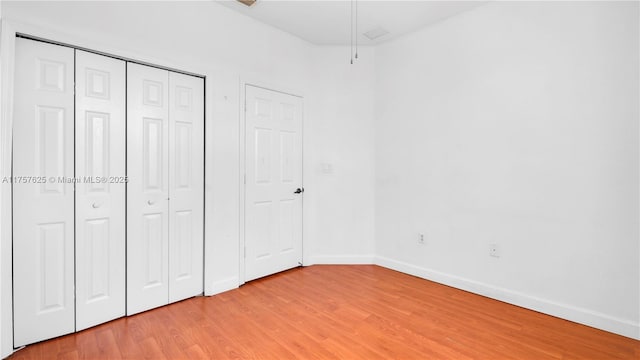 unfurnished bedroom with light wood-style floors, a closet, and baseboards