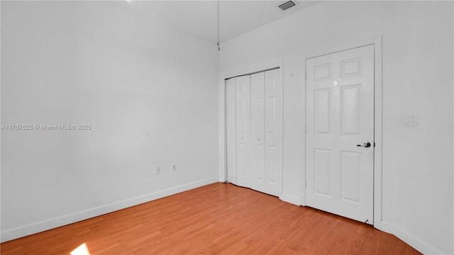 unfurnished bedroom featuring a closet, visible vents, baseboards, and light wood finished floors