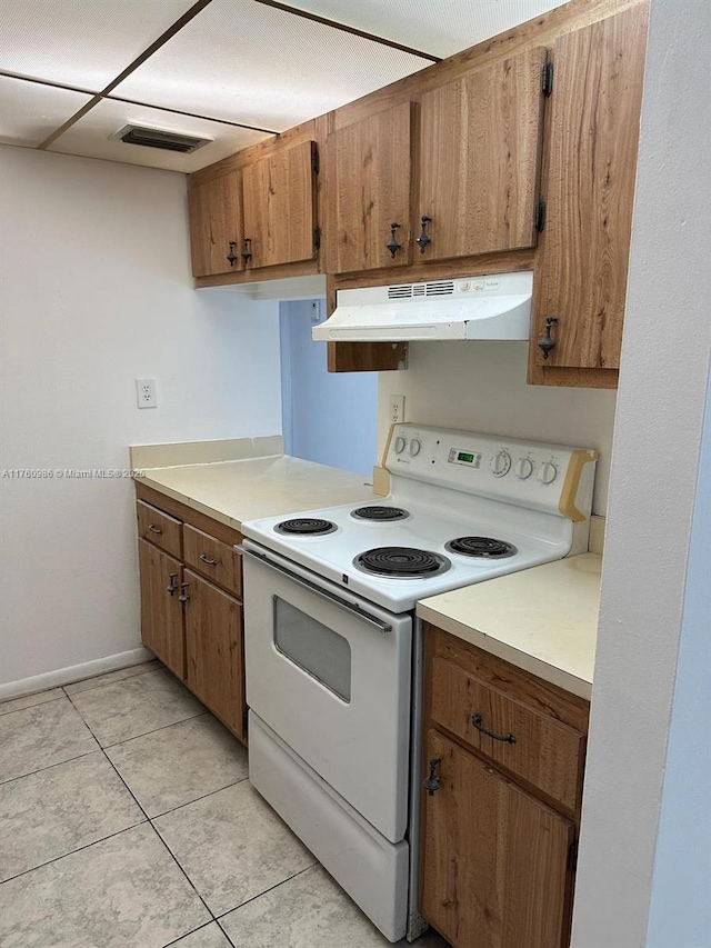 kitchen featuring brown cabinetry, visible vents, light countertops, under cabinet range hood, and white range with electric stovetop