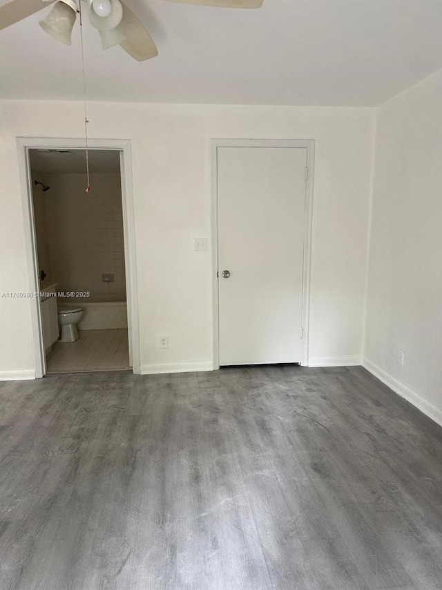 unfurnished bedroom with baseboards, wood finished floors, and ensuite bathroom