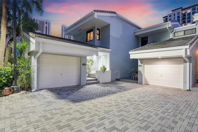 view of front of property featuring decorative driveway, an attached garage, and stucco siding