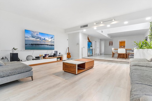 living area with light wood-style flooring, baseboards, and visible vents