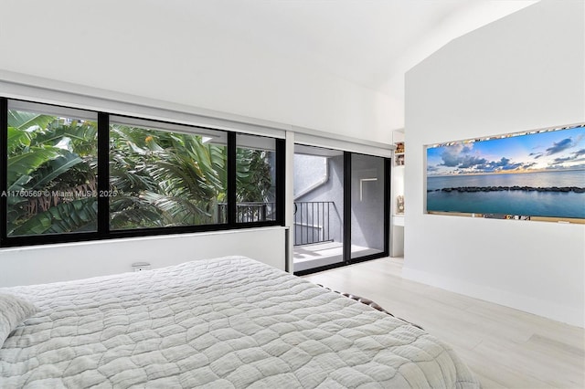 bedroom with access to exterior, a water view, baseboards, and wood finished floors