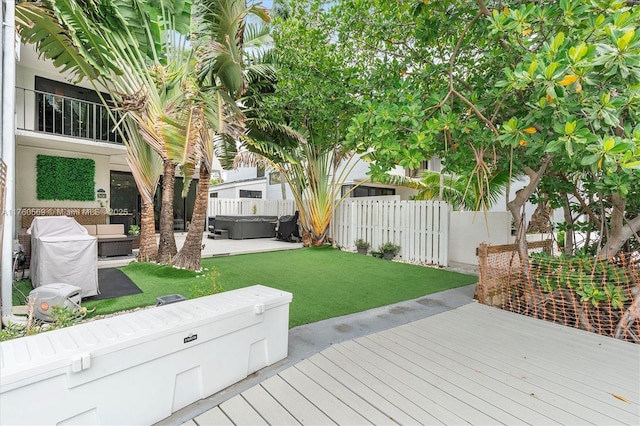 wooden terrace with a patio area, a lawn, a hot tub, and a fenced backyard