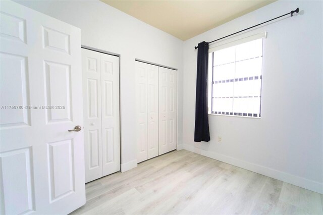 8861 W 35th Ave, Hialeah, FL 33018 - unfurnished bedroom featuring baseboards, two closets, and light wood-style floors