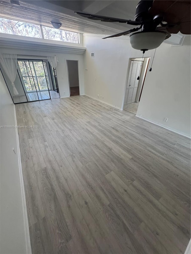 unfurnished living room featuring baseboards, ceiling fan, and light wood finished floors