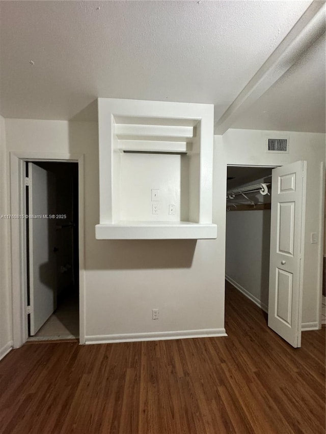 interior space featuring visible vents, baseboards, a textured ceiling, and wood finished floors