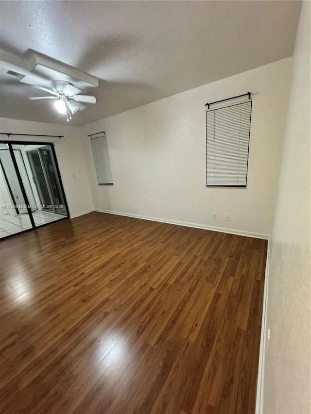 unfurnished room featuring ceiling fan, baseboards, a textured ceiling, and wood finished floors