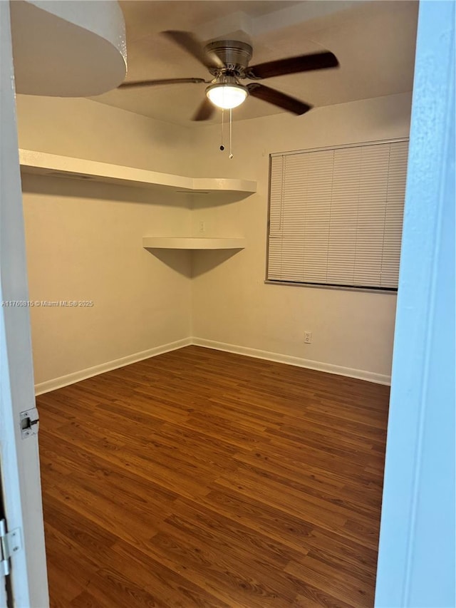 spare room featuring baseboards, dark wood-style floors, and a ceiling fan