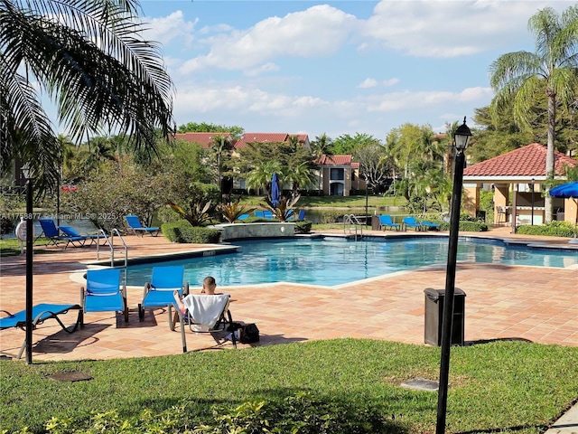 community pool with a patio and a lawn