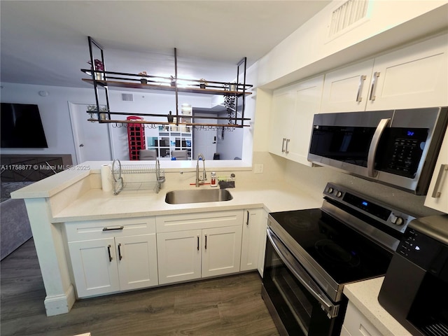 kitchen featuring visible vents, a sink, white cabinetry, stainless steel appliances, and a peninsula