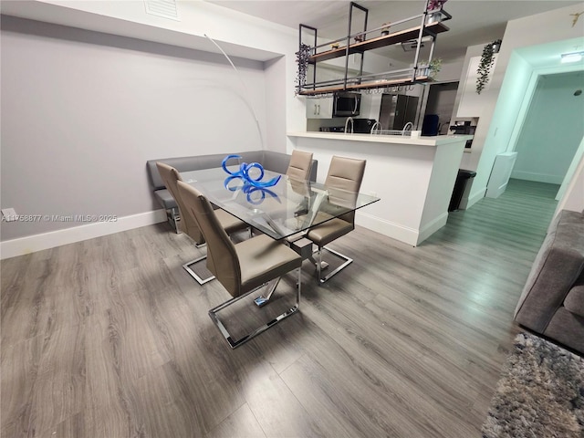 dining space featuring visible vents, wood finished floors, and baseboards