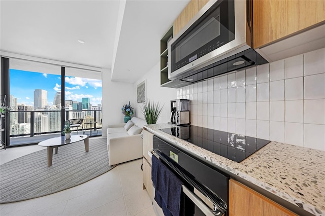 kitchen with a view of city, black appliances, expansive windows, tasteful backsplash, and light tile patterned floors