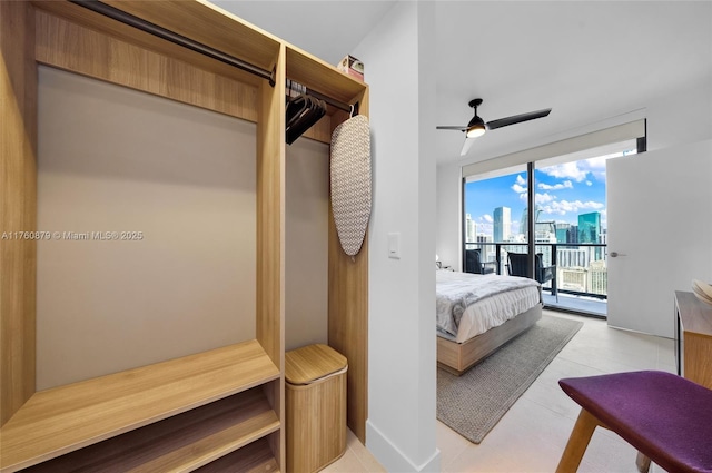 bedroom featuring access to exterior, ceiling fan, a city view, expansive windows, and light tile patterned floors