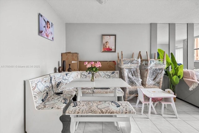 living room with a textured ceiling, tile patterned floors, and breakfast area