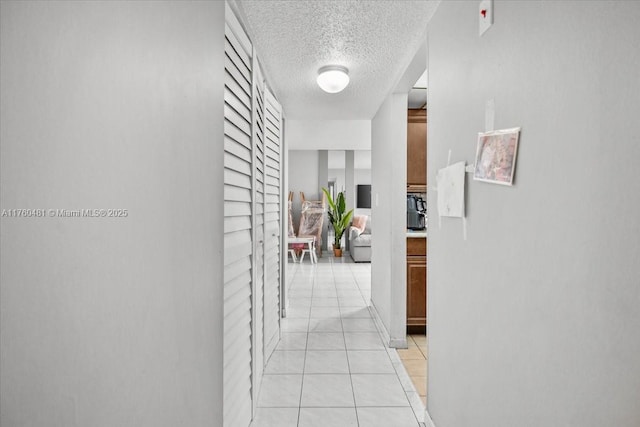 hall featuring light tile patterned flooring and a textured ceiling