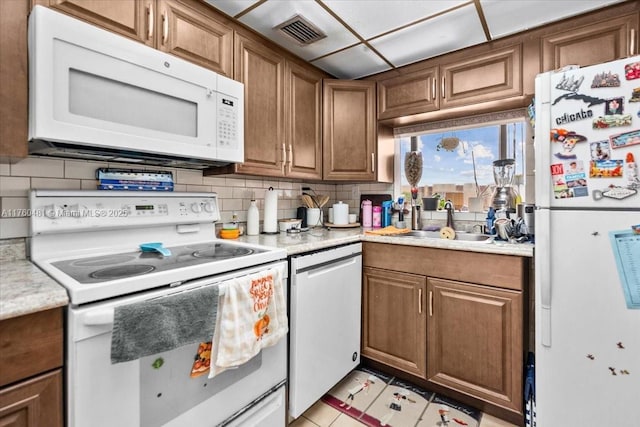 kitchen with white appliances, visible vents, a sink, light countertops, and tasteful backsplash