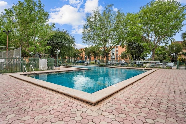 community pool with a patio and fence