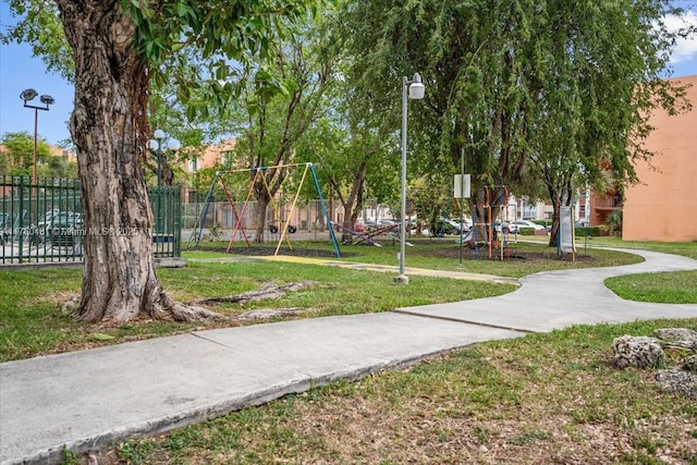 view of property's community featuring a yard, fence, and playground community