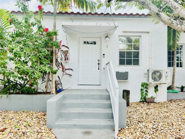 doorway to property with ac unit and stucco siding