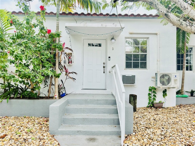 property entrance featuring ac unit and stucco siding