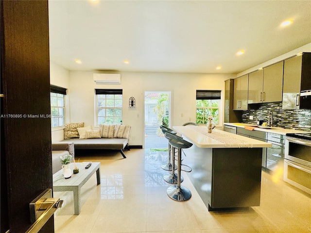 kitchen with tasteful backsplash, light countertops, an AC wall unit, a breakfast bar, and recessed lighting