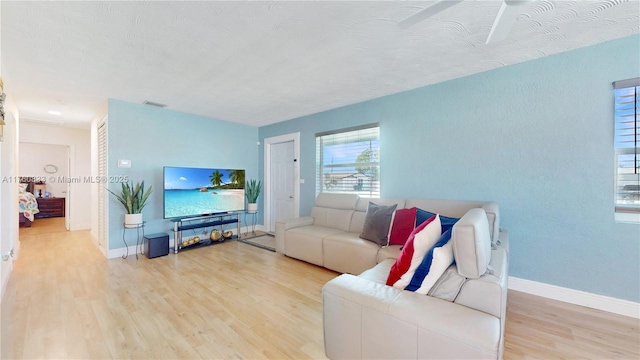 living room with visible vents, baseboards, and wood finished floors