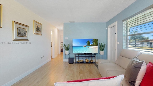 living area with visible vents, a textured ceiling, baseboards, and wood finished floors