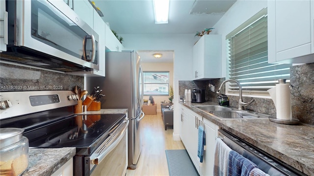 kitchen featuring white cabinets, tasteful backsplash, appliances with stainless steel finishes, and a sink