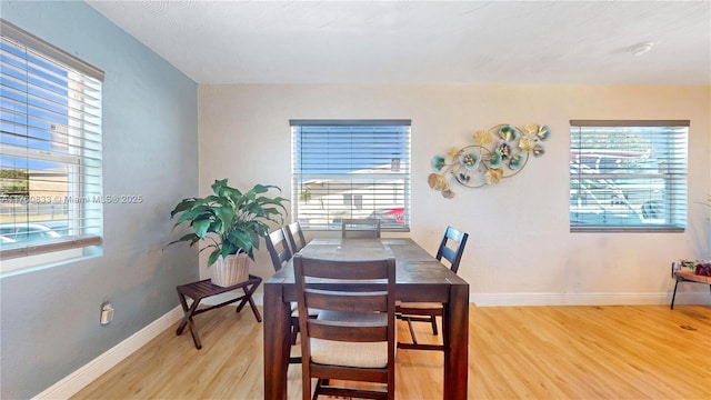 dining area featuring light wood-style flooring, baseboards, and a wealth of natural light