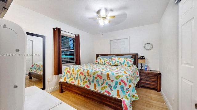 bedroom with baseboards, arched walkways, light wood finished floors, and ceiling fan