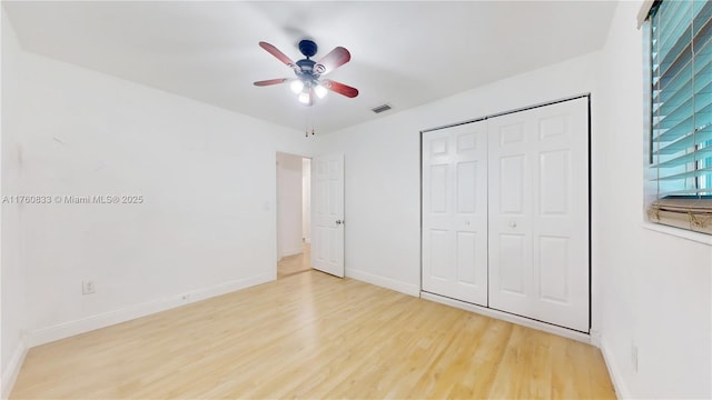 unfurnished bedroom featuring visible vents, baseboards, wood finished floors, a closet, and a ceiling fan