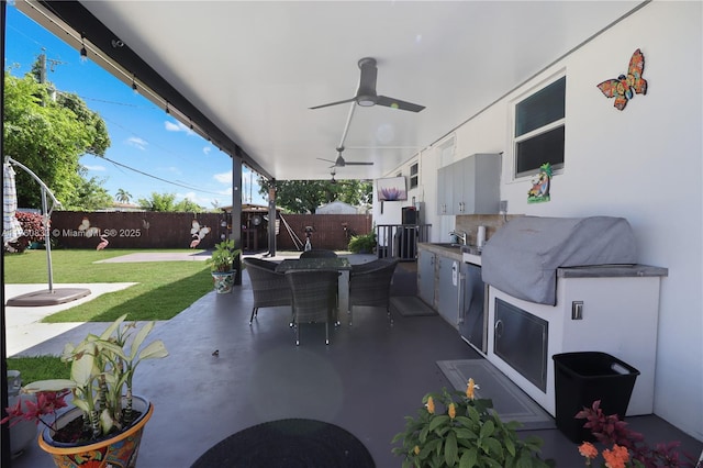 view of patio / terrace featuring a ceiling fan, a sink, a fenced backyard, outdoor dining area, and an outdoor kitchen