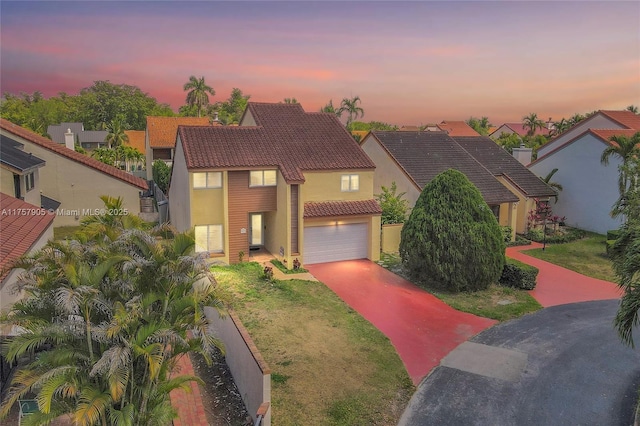 view of front of house featuring stucco siding, a lawn, concrete driveway, an attached garage, and a tiled roof