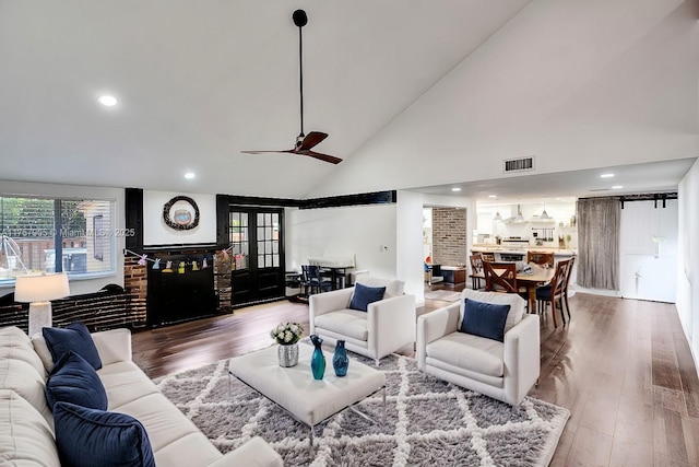 living room featuring ceiling fan, wood finished floors, visible vents, and high vaulted ceiling