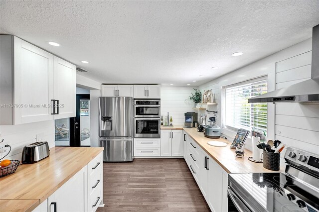 kitchen featuring visible vents, dark wood-style flooring, stainless steel appliances, white cabinets, and wood counters