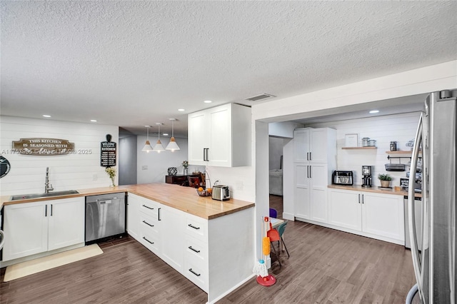 kitchen featuring a sink, stainless steel appliances, wooden counters, and dark wood-style floors