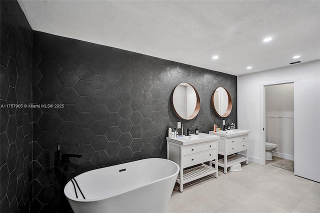 bathroom with tile patterned flooring, a freestanding bath, two vanities, recessed lighting, and tile walls