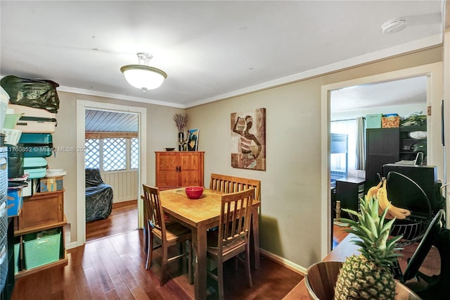 dining area featuring crown molding, dark wood-type flooring, and baseboards